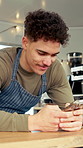 Man, barista and phone with typing for menu, social media and break in food truck cafe. Person, tech and waiter for customer service, partnership or mobile coffee shop review with communication