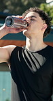 Fitness, outdoor and man drinking water on break, rest and exhausted after intense workout. Male person, tired athlete and pause to hydrate for wellness, health and training exercise in summer
