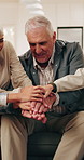 Grandparents, children and home with hands together on sofa for teamwork, mission or community. Grandpa, grandma or kids piling with stack or smile in huddle for success, support or unity in house