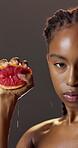 Beauty, face and grapefruit with black woman in studio for diet, health benefits or nutrition. Food, juice and squeeze with serious person on dark background for detox, skincare or vitamin c