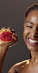 Face, grapefruit and smile with black woman in studio for diet, health benefits or nutrition. Food, juice and squeeze with happy person on dark background for antioxidants, skincare or vitamin c