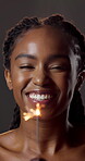 Beauty, face and sparkler with black woman in studio for celebration or satisfaction with results. Fireworks, glow and shine with happy person on dark background for skincare or vitamin c milestone
