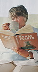 Coffee, reading book and woman on sofa in home for hobby, relax and literature for learning. Happy, mature person and drink with novel, guide or education for horticulture tutorial in living room