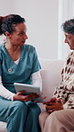 Caregiver, advice and old woman in retirement home with tablet, medical help or update for diagnosis. Nurse, talk and senior person on couch with tech, healthcare report and rehabilitation feedback.
