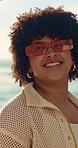 Woman, walk and sunglasses on beach with summer holiday, conversation and happy for weekend getaway. Person, stroll outdoor and smile by ocean with shades, vacation trip and discussion for travel.