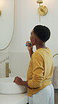 Boy, bathroom and brushing teeth in home for dental hygiene, morning routine or oral care. Kid, mirror or black child with reflection or toothbrush for cleaning mouth, bacteria or germs in house