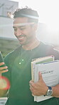Phone, smile and student walking in city for business management course or scholarship. App, learning and man with text book on university campus for academic development or study opportunity
