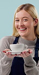 Hospitality, face or barista in studio with coffee, giving drink or friendly service with serving. Portrait, happy woman or server with warm beverage, latte handover or catering on blue background.