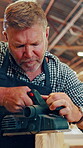 Carpenter, man and sanding in workshop with wood, power tool and precision for production process. Mature person, woodworking and manufacturing in factory for handmade, custom and orbital sander