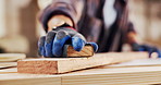 Hands, carpenter and sanding in workshop with wood, smooth surface and manufacturing process. Person, sandpaper and timber for carpentry, lumber restoration and prepare finish of furniture production