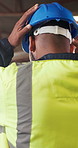 Back, engineer or man in warehouse with helmet, thinking or compliance with labor safety regulations. Person, PPE or hard hat in building with protection, civil engineering or reflection for project.