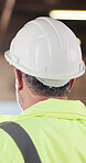 Construction, hardhat and man with inspection, risk control and site safety in building project. Protection, back or engineer with helmet, ppe compliance or hazard prevention in industrial evaluation
