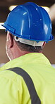 Construction, hardhat and man with inspection, risk control and site safety in building project. Assessment, back or engineer with helmet, ppe compliance or hazard prevention in industrial evaluation