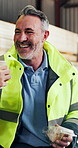 Toast, carpentry and man on coffee break, lunch and laughing at funny joke with happiness. Woodwork, mature worker and cheers with beverage, sandwich and humor in furniture production warehouse