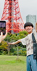 Travel, photography and couple with phone for bonding, capturing moment and tourism or content creation. Outdoor, influencer and people in city, photographer and picture of Tokyo Tower in Japan