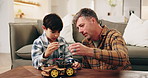 Dad, kid and building with toy car in home for assembling parts, bonding or fun activity together. Father, child or helping son on electrical motor vehicle for junior engineering or learning in house