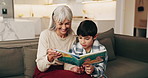 Grandmother, child and reading book in home for learning, storytelling and bonding together. Literacy skills, smile and boy with grandparent on sofa for education, wisdom and language development