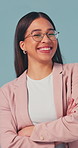 Face, businesswoman and smile in studio with arms crossed, glasses and pride for creative career. Confident, person and happy with marketing job, positive attitude and ambition on blue background.