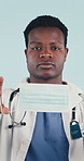 Face, healthcare and doctor in studio with mask for tutorial, safety and thumbs up for prevention. Portrait, emoji and black man in ppe for wellness, protection or hygiene approval on blue background