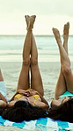 Beach, women and friends relax with legs up on holiday, vacation or travel together on tropical island. Outdoor, girls and group lying by ocean on blanket for playful, rest or tan in summer with feet