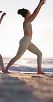 Stretching, beach and woman as yoga instructor on exercise mat for fitness, warrior pose and wellness. Happy person, group and sunrise by ocean for mindfulness, self care and peace outdoor in nature