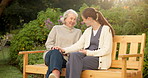 Talking, nurse and senior woman on bench for bonding, support and conversation in fresh air. Retirement, happy and caregiver with elderly person for chat, laugh and joke for wellness, care and relax