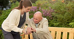 Nurse, helping and senior man with cane on bench for assisted living in outdoor garden or park. Female person, caregiver or aid with elderly patient or walking stick for mobility or support in nature
