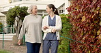 Talking, caregiver and walking with old woman outdoor, support and laugh at funny joke. Nurse, retirement and help with person at garden of home, conversation and humor for healthcare assistance