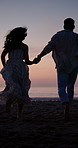 Sunset, couple and holding hands at beach for running, travel adventure or love for summer holiday. Back, evening or people outdoor by ocean with relationship, romantic getaway or bonding on vacation