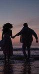 Sunset, couple and holding hands in sea for running, love and travel adventure for summer holiday. Evening, silhouette or happy people outdoor at beach with relationship, romantic getaway or vacation