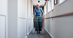 Senior, woman and hallway with walker in retirement apartment for mobility or movement in house. Elderly, female person or walking with aid or help for assistance, balance or recovery in nursing home
