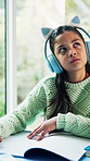 Child, homework and thinking in house with headphones, music and writing answer for education task. Girl, problem solving and learning in home with notes, audio tech and school assessment with radio.