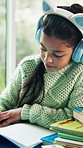 Child, headphones and writing in house with homework, music and problem solving for education task. Girl, study and learning in home with audio tech, kids radio and notebook for school assignment.