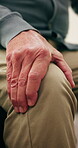 Hand, knee pain and senior person in home for symptoms of arthritis or chronic osteoporosis. Injury, joint and massage with elderly man in living room of apartment for discomfort or swelling