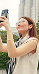 Travel, picture and Asian woman in city with phone, tourist holiday and capture memories of trip. Happy, Japanese person and outdoor in urban town with tech, walk and vacation photography in Tokyo.