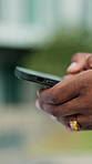 Person, hands and typing with phone in city for social media, communication or network connection. Closeup, user or texting with smartphone for mobile chatting app, software or research in urban town