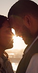Sunset, couple and love at beach with connection, care or smile for bonding together on outdoor date. Flare, happy people and forehead touch by ocean with romantic relationship, peace and evening.