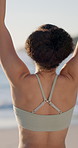 Yoga, beach and back of woman with stretching, exercise or wellness routine in morning on holiday. Health, outdoor and person by ocean for fitness, active and pilates by seaside on weekend trip.