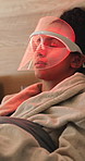 Beauty, mask and woman with red light therapy on bed in home for skincare, relax or wellness. Health, calm and person with infrared LED treatment for dermatology with collagen production in house.