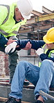 Architect, man or helping hand with injury on construction site for building accident or fall. Male people, civil engineer or contractor with assistance, aid or helmet for safety, security or mistake