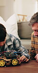 Boy, dad and toy car with cables in home for electrical engineering or remote control vehicle. Child, kid or learning with father to build robotic transportation for junior mechanic or development