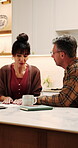 Couple, finance and documents with laptop in kitchen for mortgage payments, bills or investment. Mature man, woman and discussion with paperwork on computer for financial planning or invoices in home