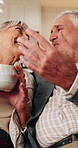 Tea, kiss and senior couple with laugh in home for funny chat, healthy marriage or connection. Affection, happy people or conversation joke with drink in house for bonding, retirement support or love