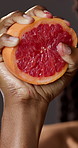 Hands, squeeze and person with grapefruit in studio for wellness, healthy diet and vitamin c. Dark background, hydration and woman with fruit for nutrition, clean eating and antioxidants for detox