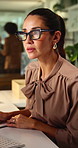 Businesswoman, writing and serious with glasses in office, thinking and financial updates on website. Reflection, treasury manager and mature person with eyewear, online or risk assessment with notes