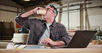 Man, coffee and carpenter in workshop with laptop for research on furniture manufacturing. Computer, cappuccino and mature woodworker with email for order confirmation with contact in warehouse.