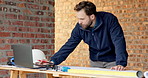 Man, laptop and drawing on construction site for blueprint, inspection or update planning. Infrastructure, quality control and architect with tech, report or project management for renovation