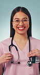 Doctor, face and happy with stethoscope in studio for medical service, cardiology intern or pride. Healthcare, woman or smile on blue background for medicine expertise, career integrity or confidence