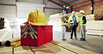 Carpentry, helmet and toolbox in warehouse with people talking for manufacturing or production. Collaboration, engineering and hardhat with designer team in woodworking factory for discussion