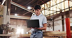 Man, carpenter and reading in workshop with laptop, research and review design for production. Intern, person and pc in factory for carpentry, online blueprint and policy for manufacturing furniture